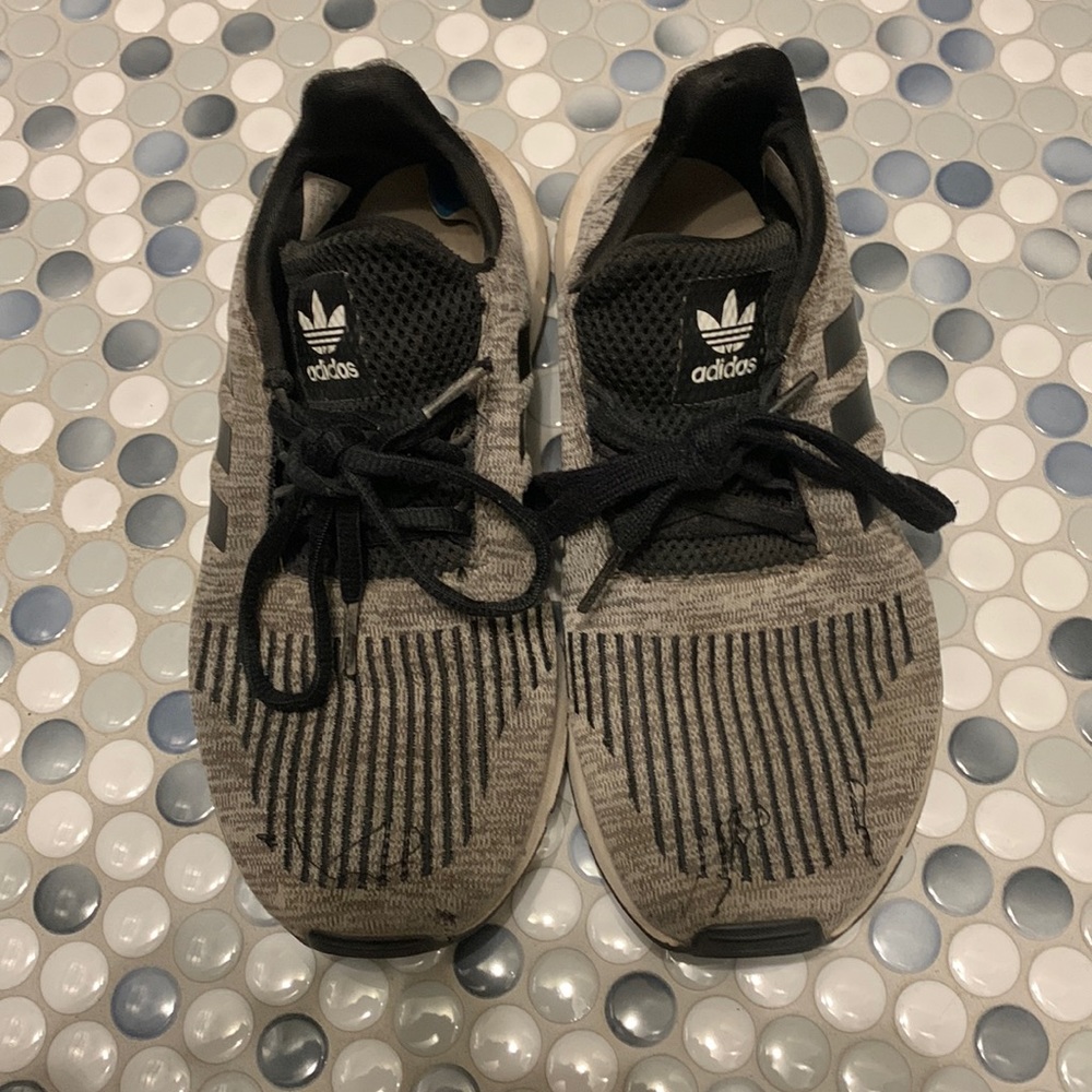 Very used black and gray adidas tennis shoes, loose threads. Size 4 1/2